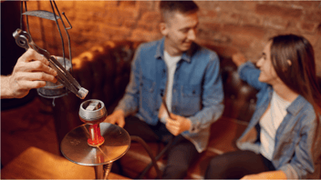 Young couple sitting at a table with a hookah