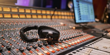 A sound board with headset, mean to represent the workspace of someone managing in-store retail media and audio production