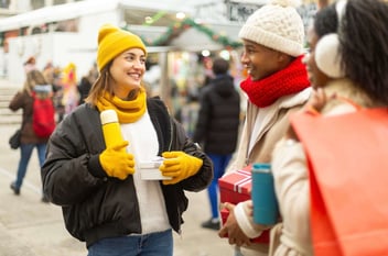 Friends in a shopping area exchanging gifts, meant to show the power of holiday music for business