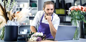 Man looking at digital signage reports in retail store, meant to indicate the power of digital signage KPIs to drive results