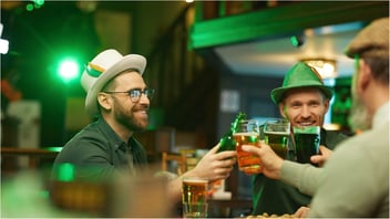 Men in festive attire drinking at a bar, meant to represent the potential of a great St. Patrick's day playlist for bars and restaurants.