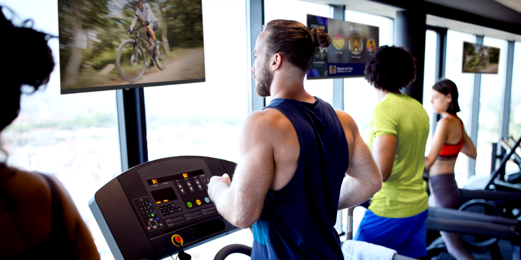 Gym member engaged with TV while working out