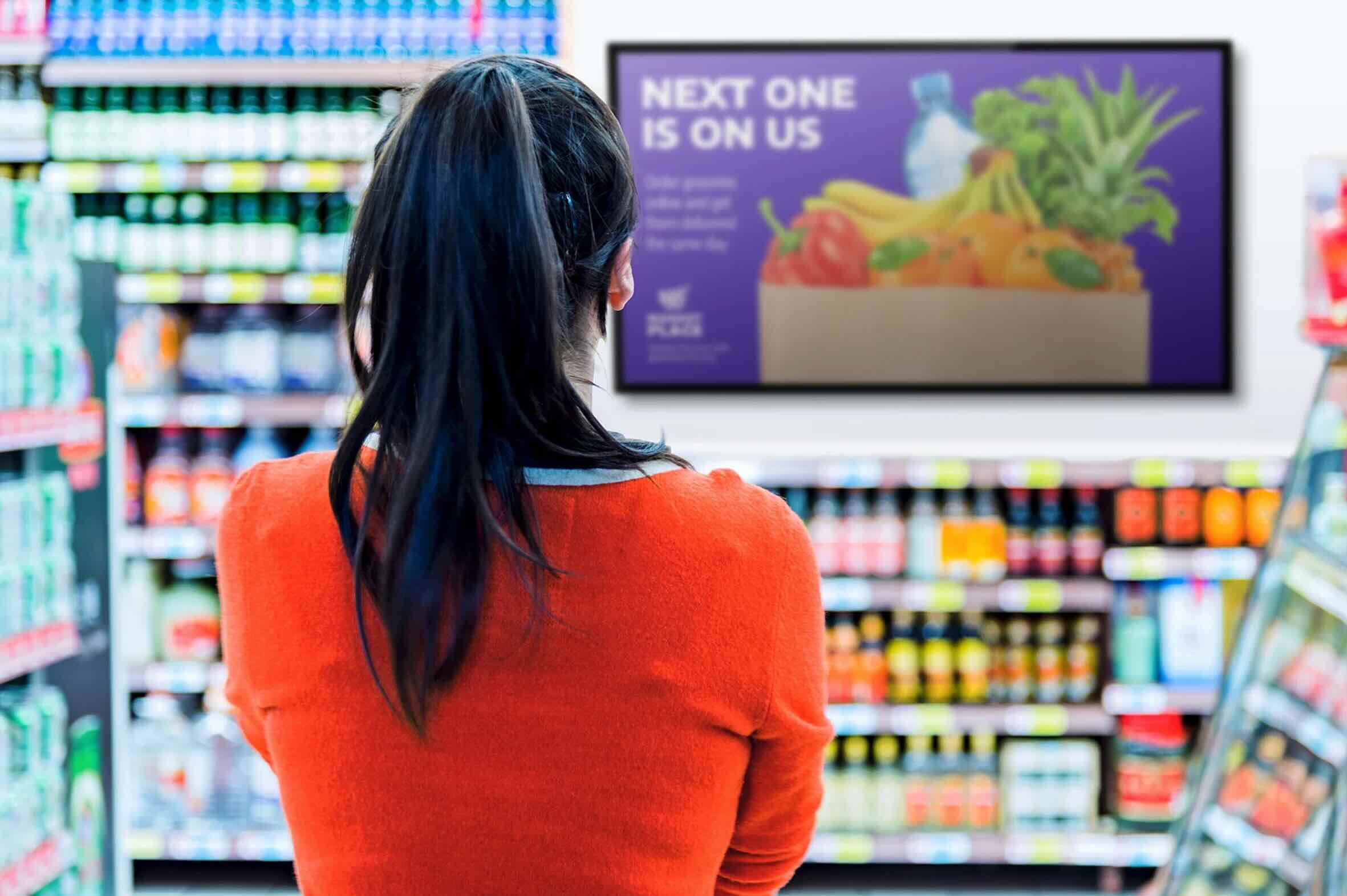 A woman looking at a grocery story promotion meant to represent the power of digital signage for grocery