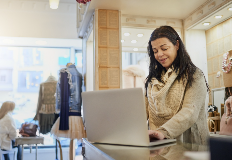 Woman looking at a laptop in a retail store, meant to represent the importance of digital signage KPIs